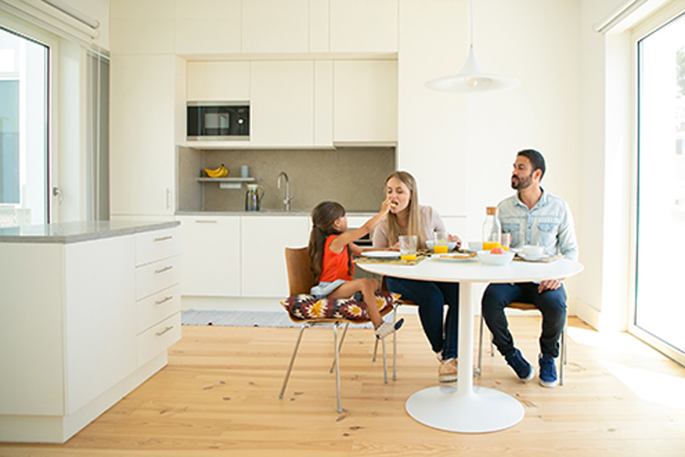 Family sitting at dining table together and having breakfast.