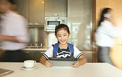  2021/10/girl-tablet-kitchen-245-155.jpg Daughter playing on digital tablet while parents running around