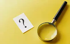  2021/10/magnifying-glass-245.jpg Magnifying glass with printed question mark lying side by side on a yellow background in a conceptual image viewed from above