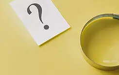  2021/10/magnifying-glass-question-mark-245.jpg Magnifying glass with printed question mark lying side by side on a yellow background in a conceptual image viewed from above