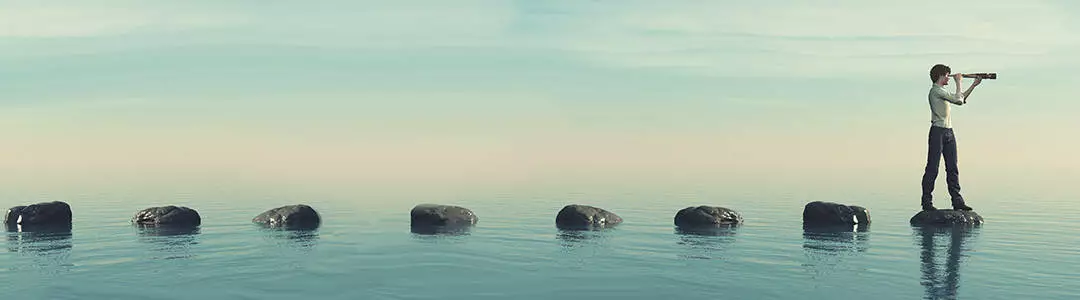  2021/10/steps-discover-1080-2.jpg The young man sits on a large stone in the middle of the sea and looks through the binoculars. This is a 3d render illustration