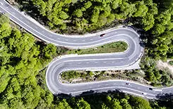  2021/10/winding-road-245.jpg Winding road in the forest. Transylvania, Romania, Europe. Cars passing on road.