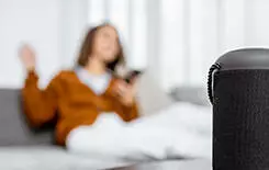  2021/10/woman-controlling-home-devices-with-a-voice-245.jpg Smart wireless column with a young woman controlling home devices with a voice commands on the background at home