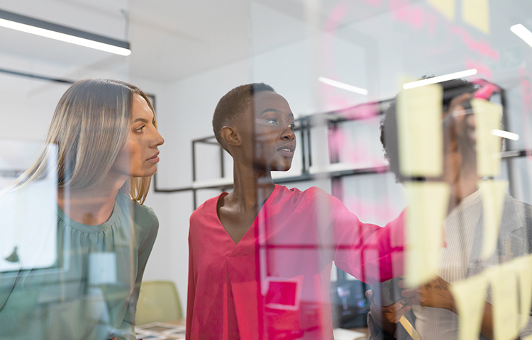 colleagues brainstorming using glass wall in meeting room. business in a modern office.