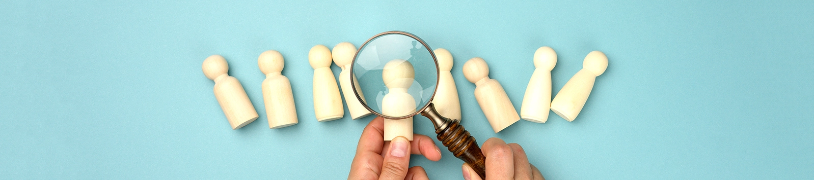 wooden figures and magnifying glass on blue background