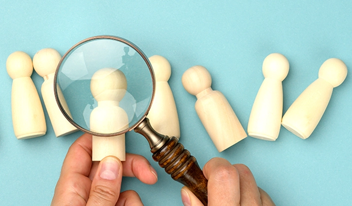 wooden figures and magnifying glass on blue background