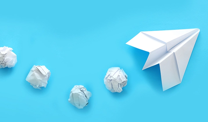 Innovation concept - paper airplane and crumpled balls of paper