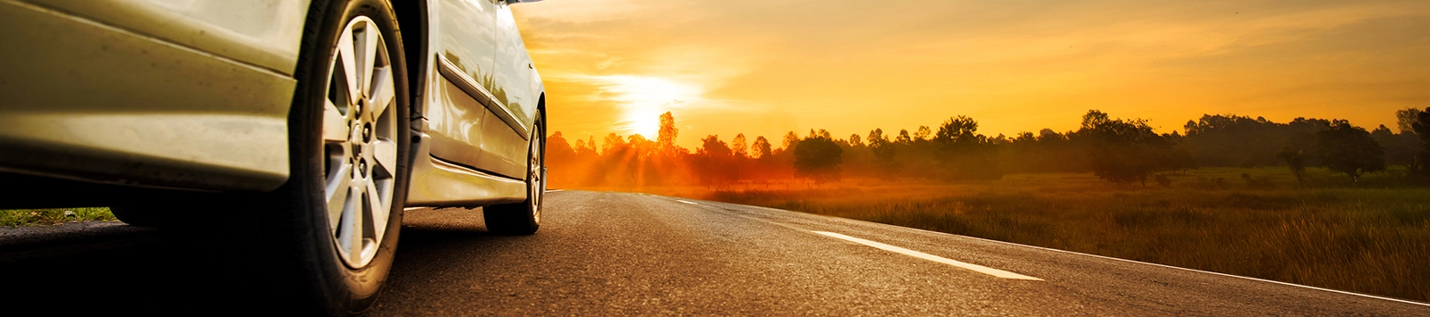 Close-up of car driving on highway with sunset and landscape