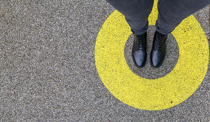 person standing in a yellow circle with asphalt background below