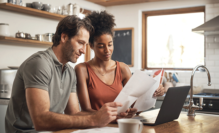 Couple using their laptop and going through finances and paperwork at home