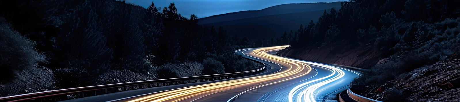 Cars light up trails at night on a curved paved road at night. 2024/03/lights-on-road-1800-02.jpg 