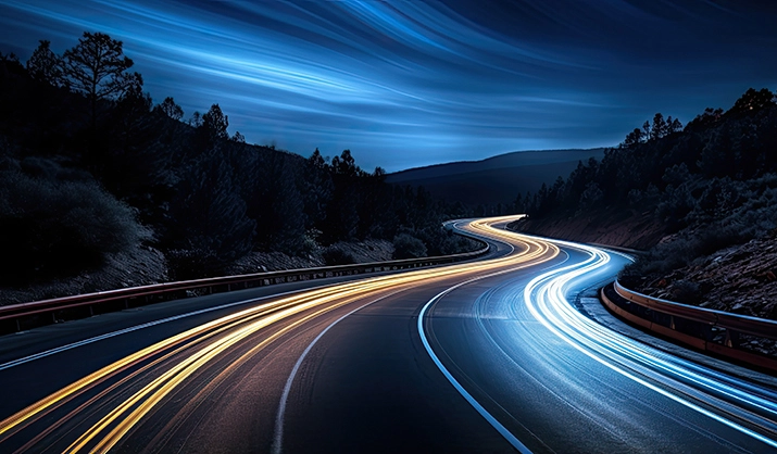 Trails of car headlights on a curved road at night
