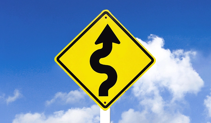 Road sign for a curvy road in front of a blue sky