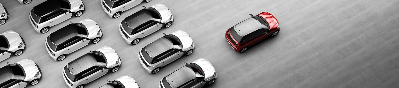 One red car stands out in a group of silver cars