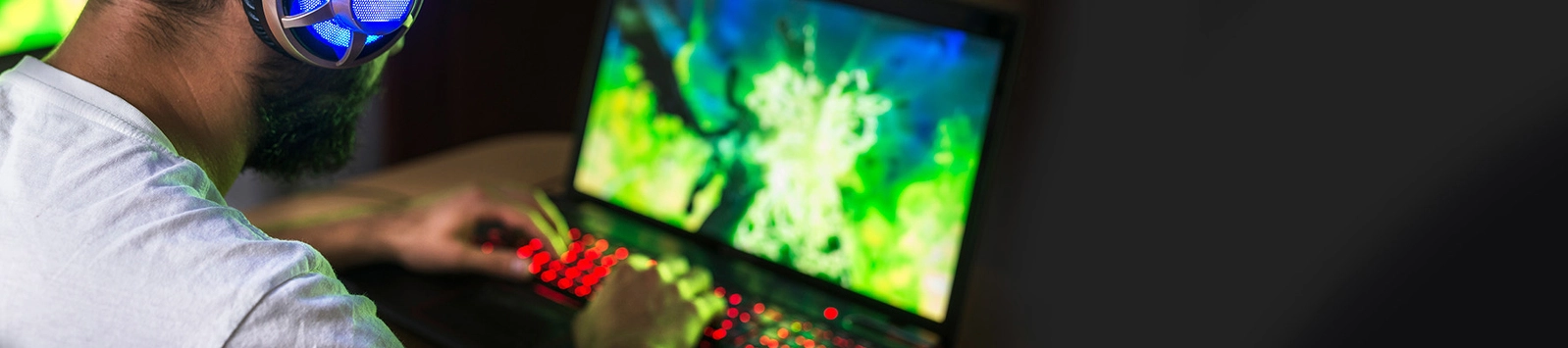 gamer playing video game on laptop wearing headphones