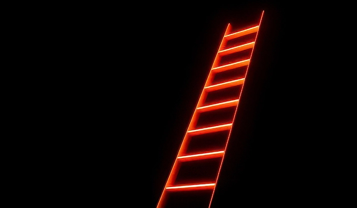 Illuminated ladder with bright orange-red lines against black backdrop