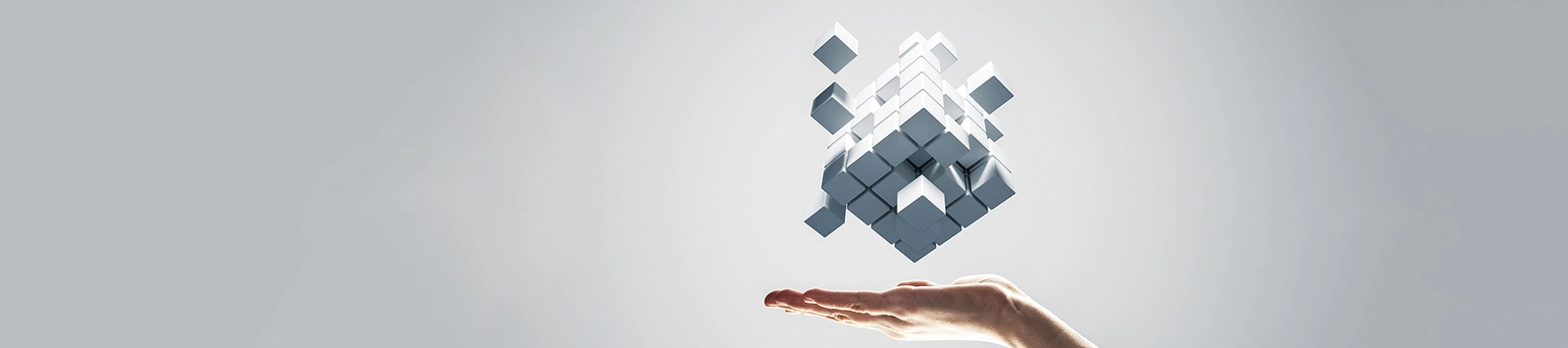 Conceptual image of innovation: cubes combining to form a new shape above an outstretched hand