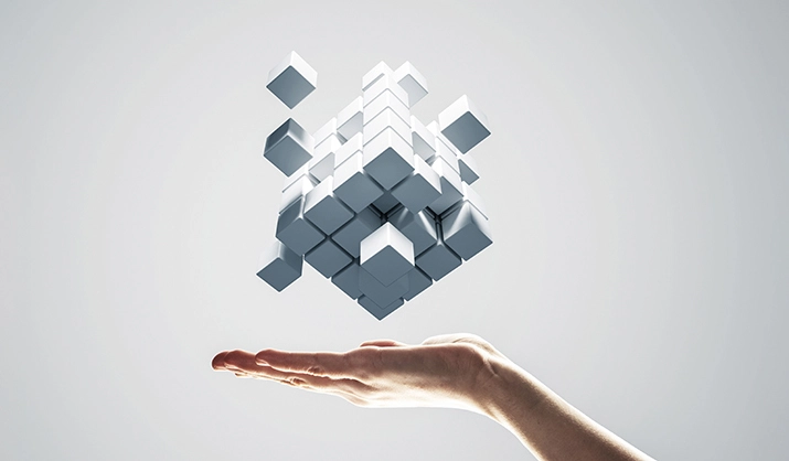 Conceptual image of innovation: cubes combining to form a new shape above an outstretched hand